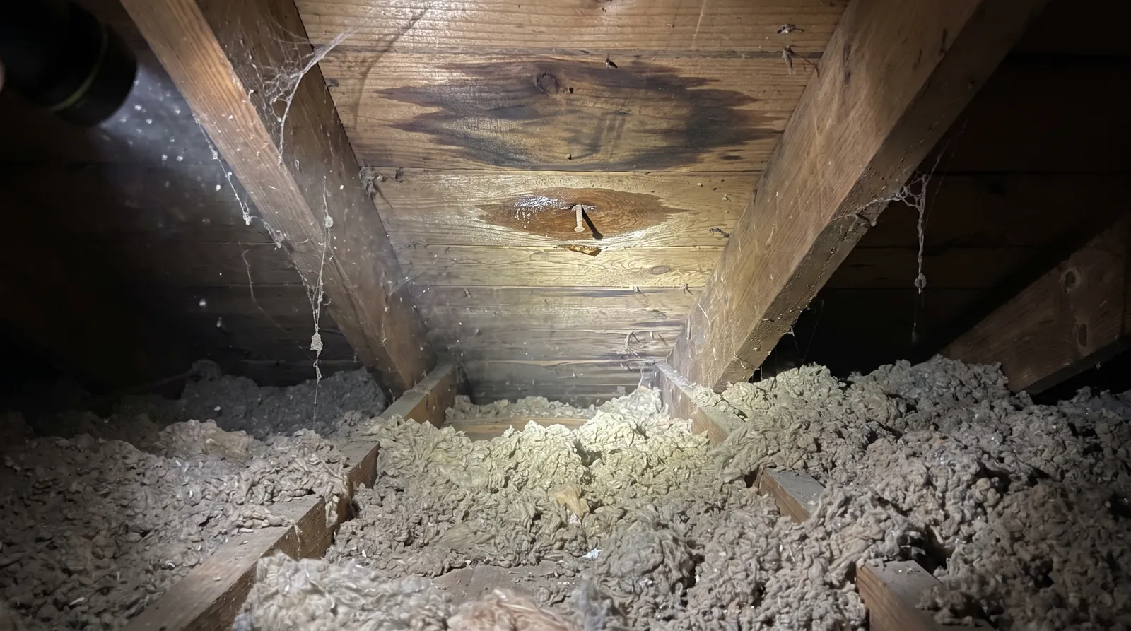 Attic view of a water stain on roof decking below a valley